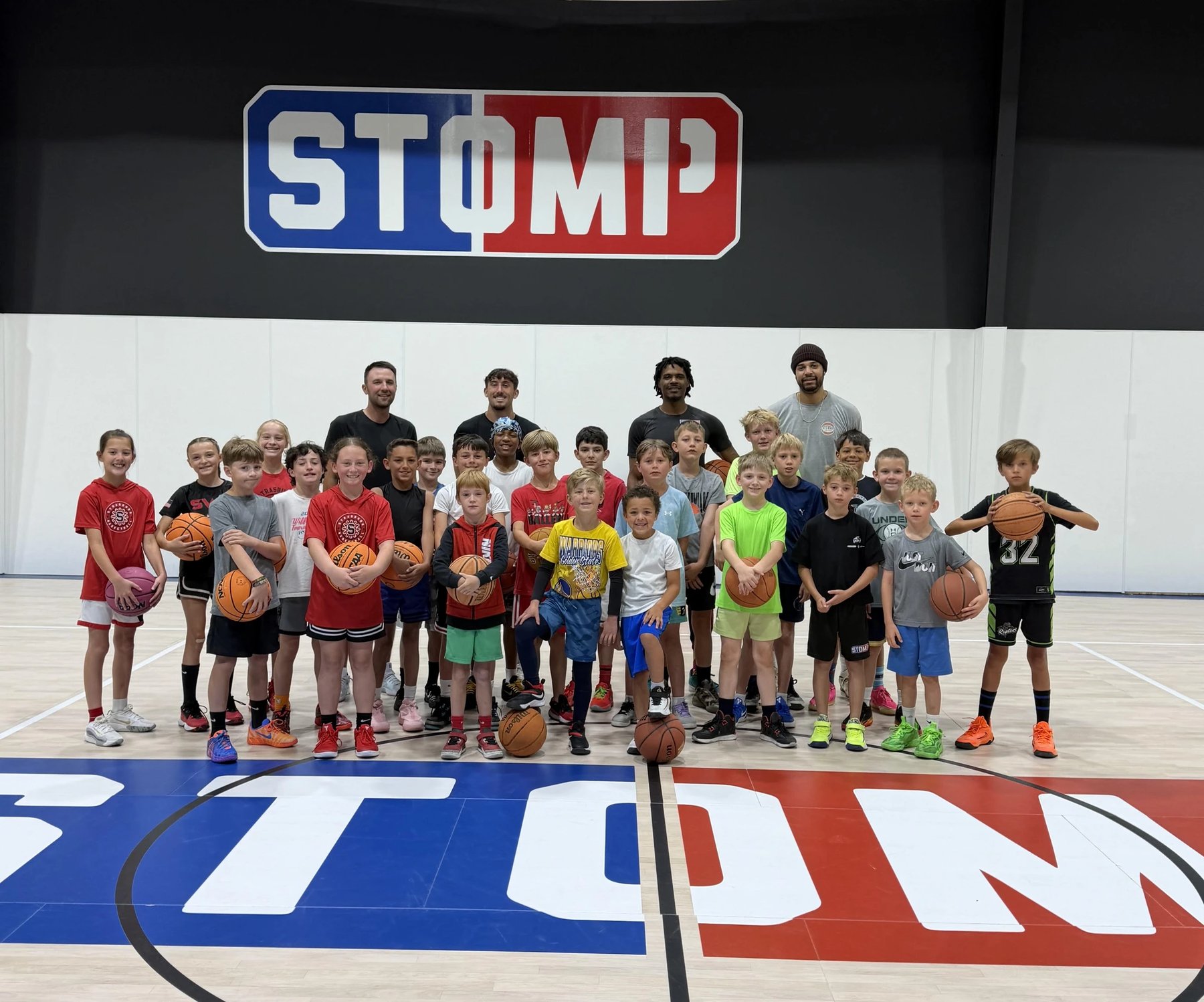Campers and coaches gathered at center court under the STOMP sign after the last STOMP Training camp